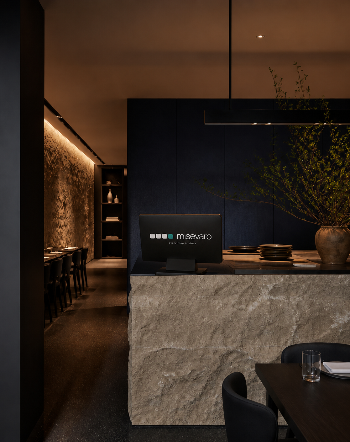 Misevaro-branded reception counter monitor in a moody minimalist restaurant interior
